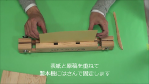 表紙と原稿を重ねて製本機に挟んで固定します